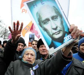 昨年12月10日、老いたプーチン氏の肖像を掲げ、ロシア下院選の不正に抗議する人々 （C）AFP=時事