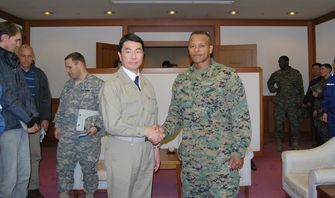 表敬に訪れた日米共同調整所の米軍側指揮官クレイグ・ティンバーレイク大佐（右）と握手する宮城県の村井嘉浩知事 （C）時事