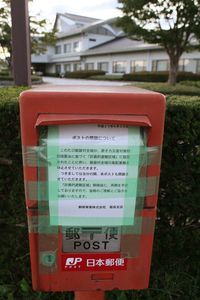 村全域が計画的避難区域に設定されたことに伴い閉鎖された郵便ポスト。後方は飯舘村役場　（C）時事