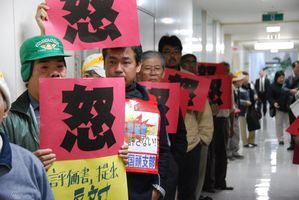 昨年12月28日、環境影響評価書が入っているとみられる段ボール箱が運び込まれた沖縄県庁守衛室前に集まった約70人の反対派住民 (C)時事