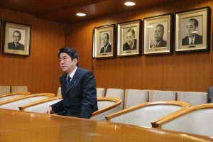  自民党総裁室の椅子に座る安倍晋三総裁。壁面右端の顔写真が祖父・岸信介氏 （C）時事